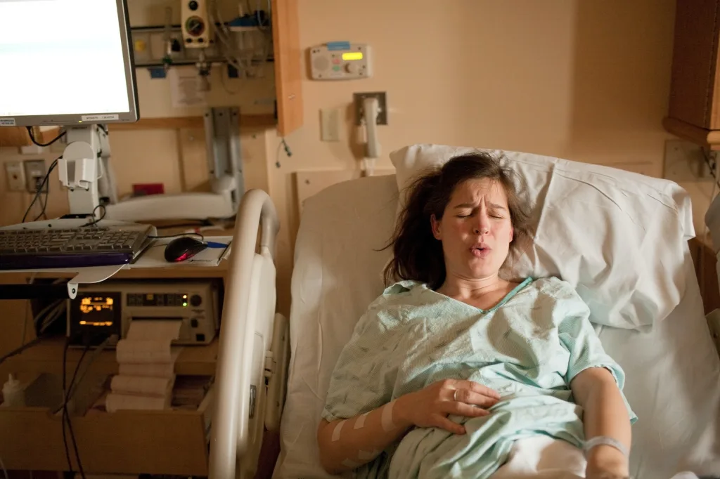 Schwangere Frau in den Wehen auf dem Krankenhausbett
